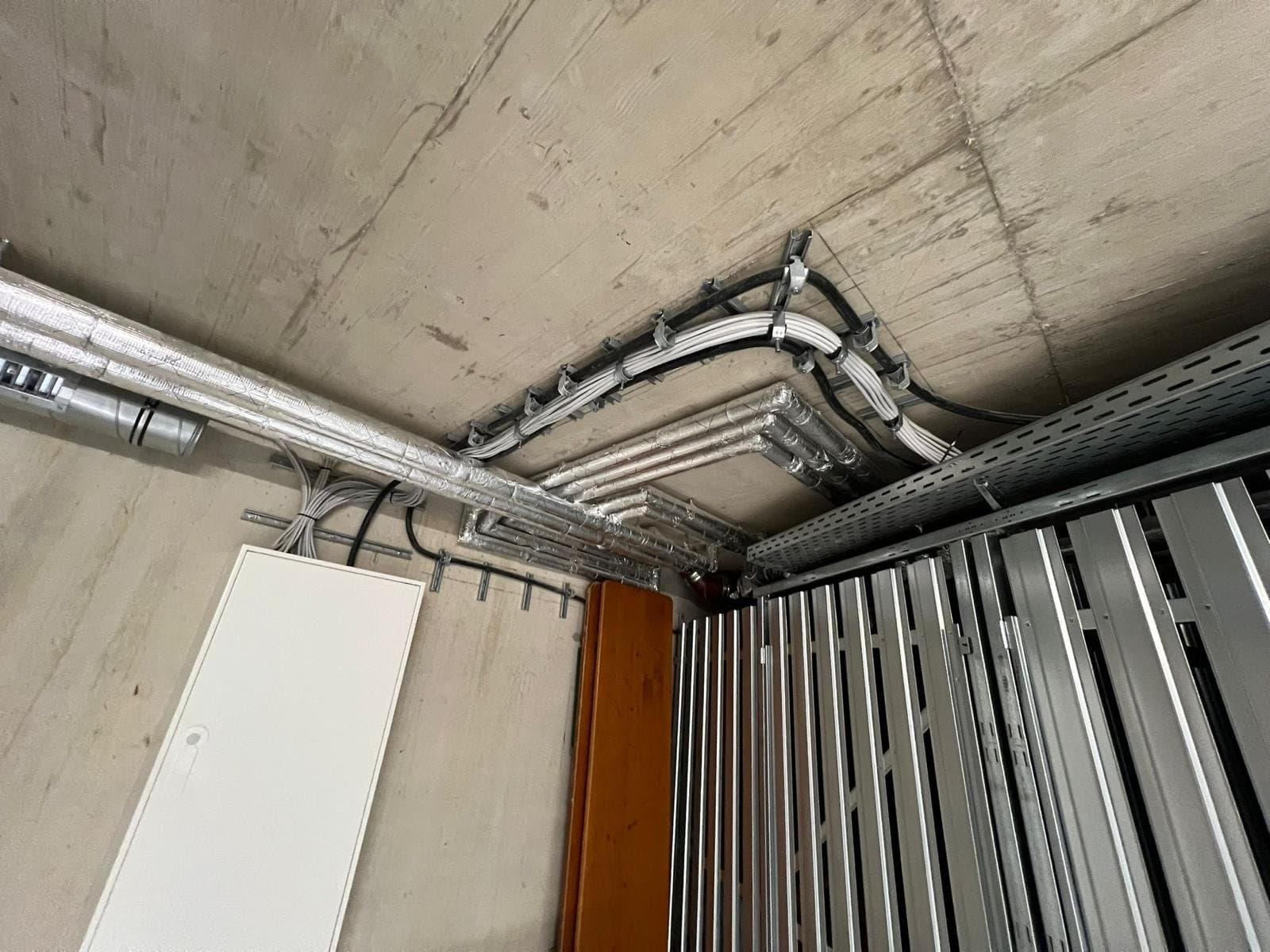 Kabeltrassen mit sauber geführten Leitungen an einer Betondecke im Rohbau