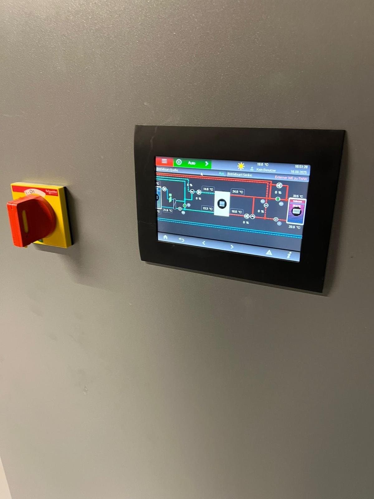Wandmontiertes Touch-Bedienpanel einer Gebäudesteuerung neben einem Hauptschalter